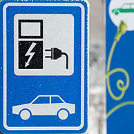 Electric car charging station sign at car park in the snow in winter, Belgium